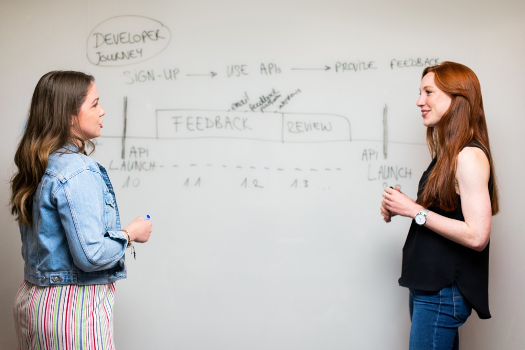 Women Talking Next to Whiteboard