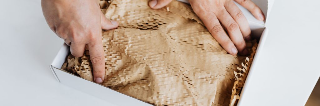 man packing a box with honeycomb packing paper