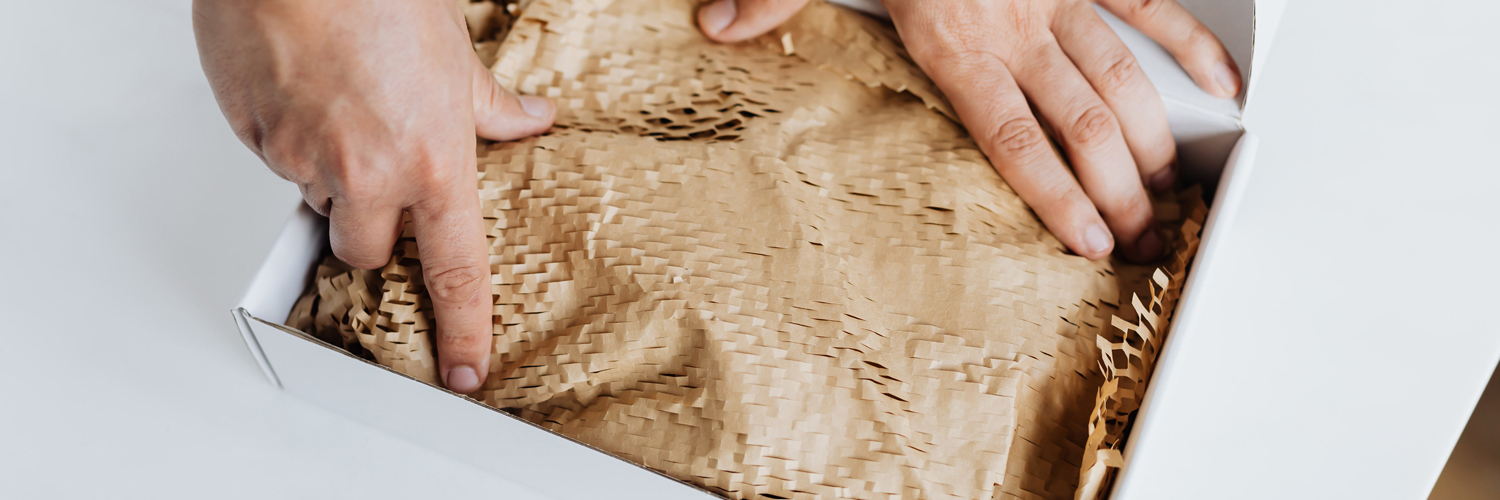 man packing a box with honeycomb packing paper