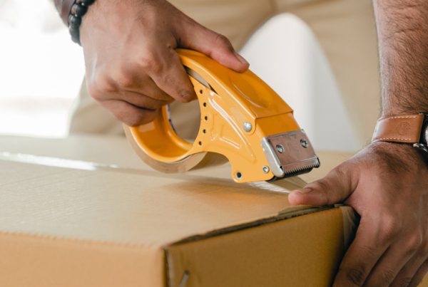 man taping box with tape dispenser