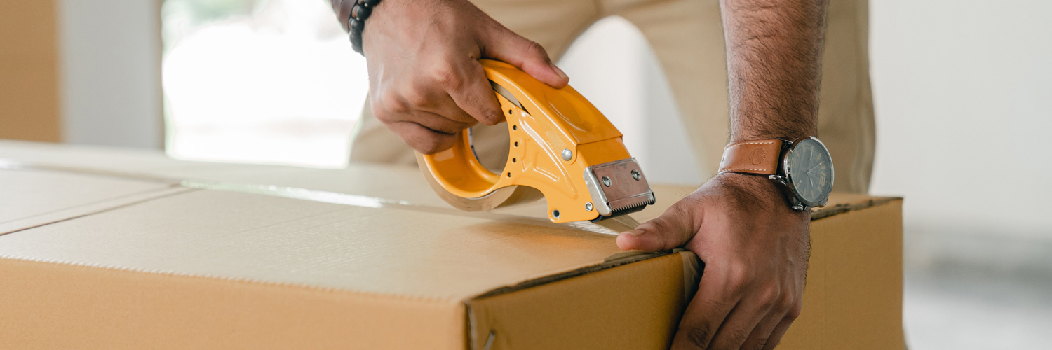 man taping box with tape dispenser