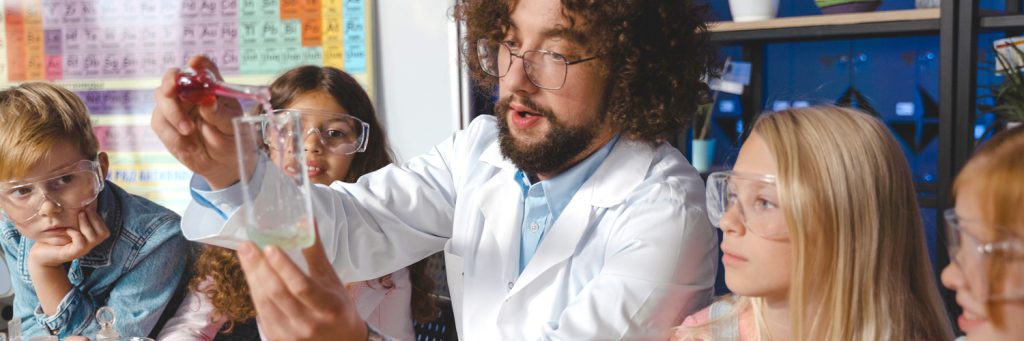 science teacher showing four students a reaction that two substances have with one another
