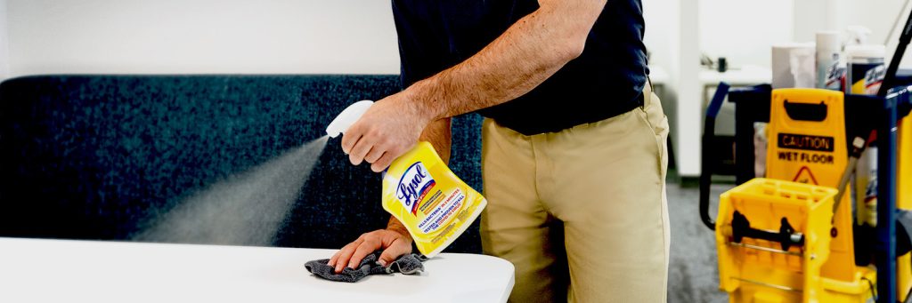 Man spraying Lysol spray onto table