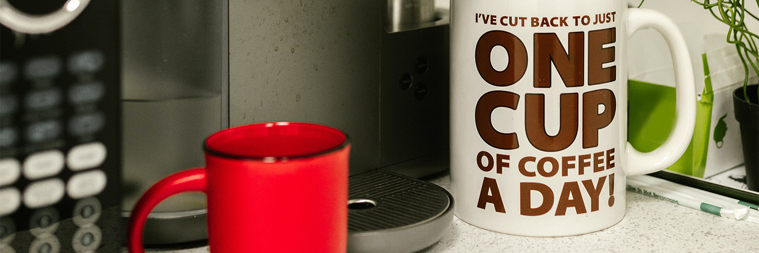 Coffee cups and machine on countertop