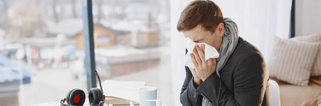 man sitting at desk sneezing