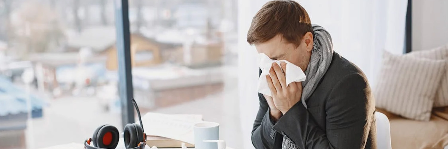 man sitting at desk sneezing