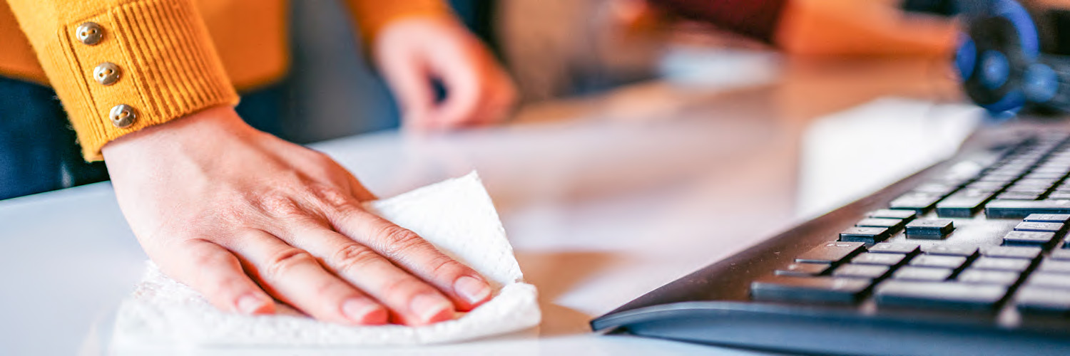 person wiping off computer with wipe