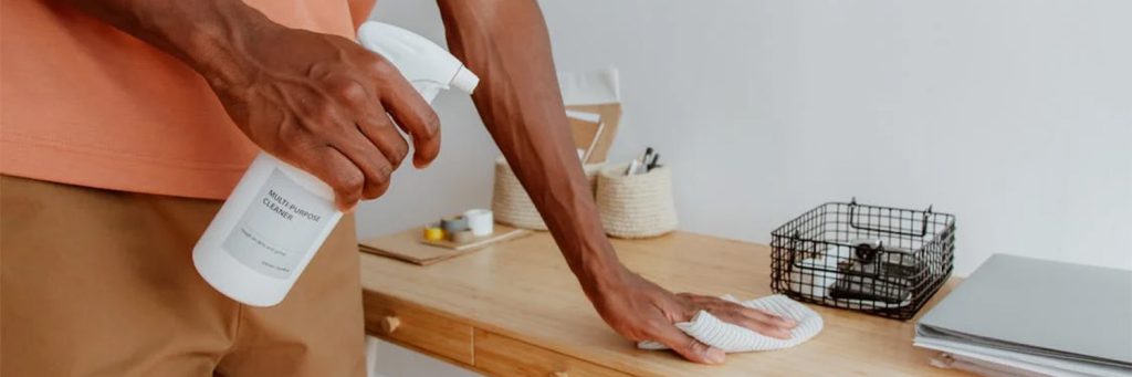 man cleaning desk with spray