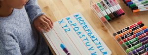 Whiteboard and Expo® whiteboard accessories being used to practice writing the alphabet
